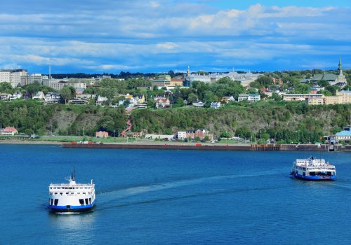 Ferry boat in river in Quebec City with blue sky.